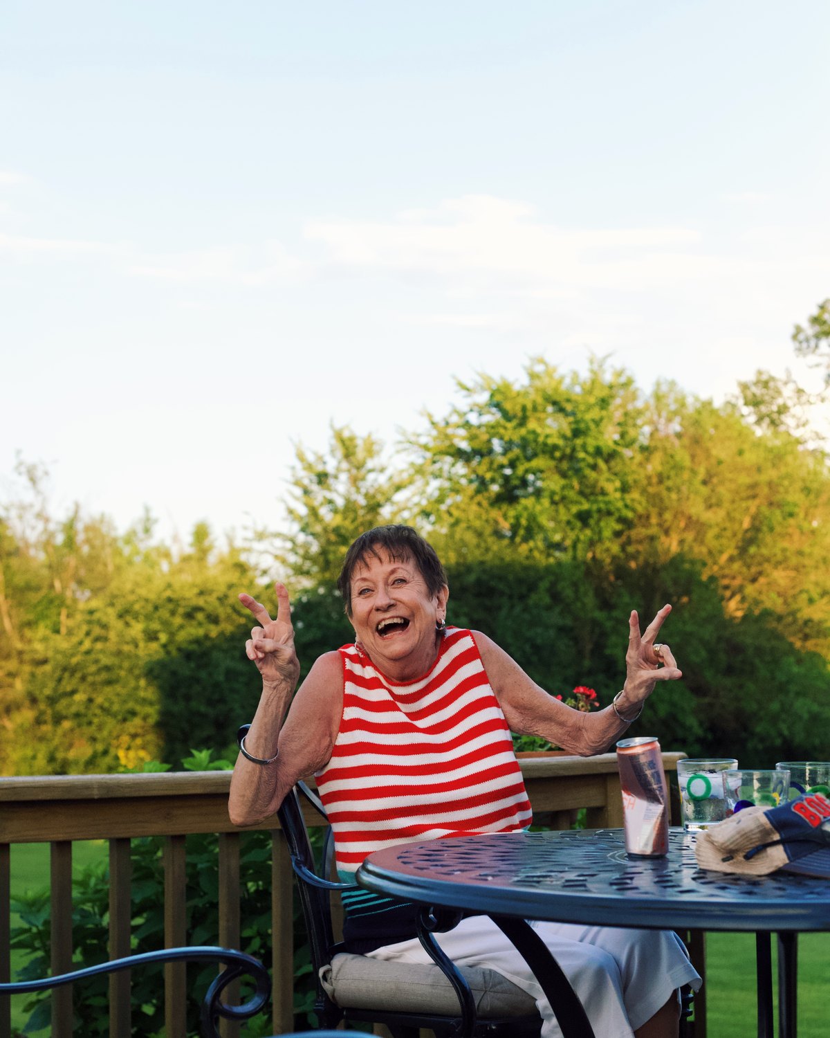 A woman laughing outdoors at a community photography event, both hands raised