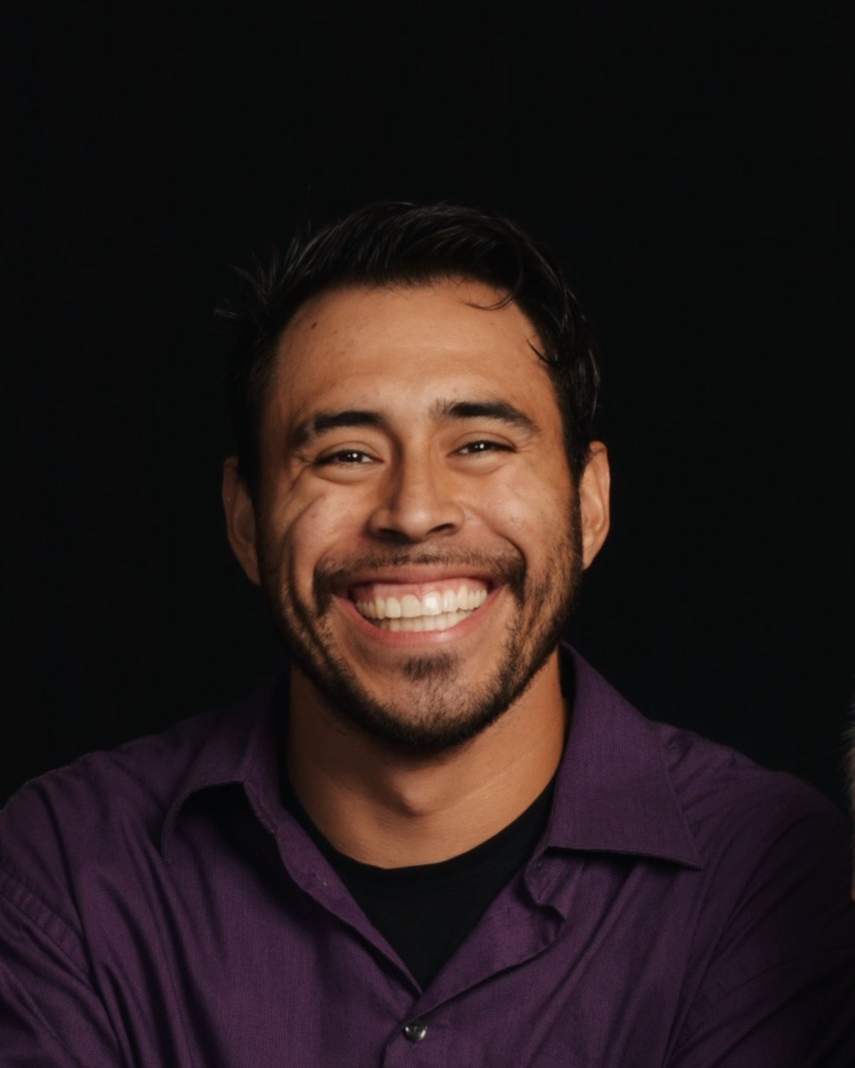 Lorenzo Marez, founder of Seniority Photo Group, laughing against a black backdrop