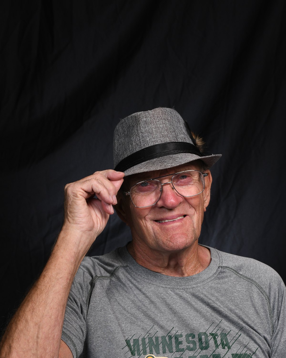 Portrait of a man tipping his grey fedora and smiling
