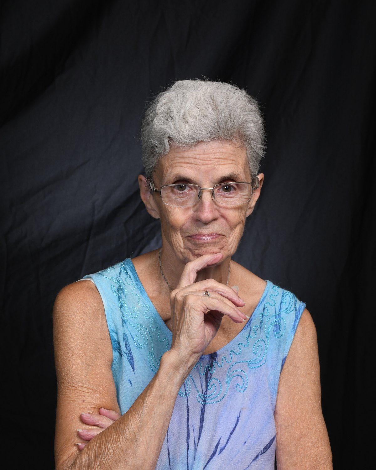 Portrait of a woman resting her chin on her hand, looking directly at the camera