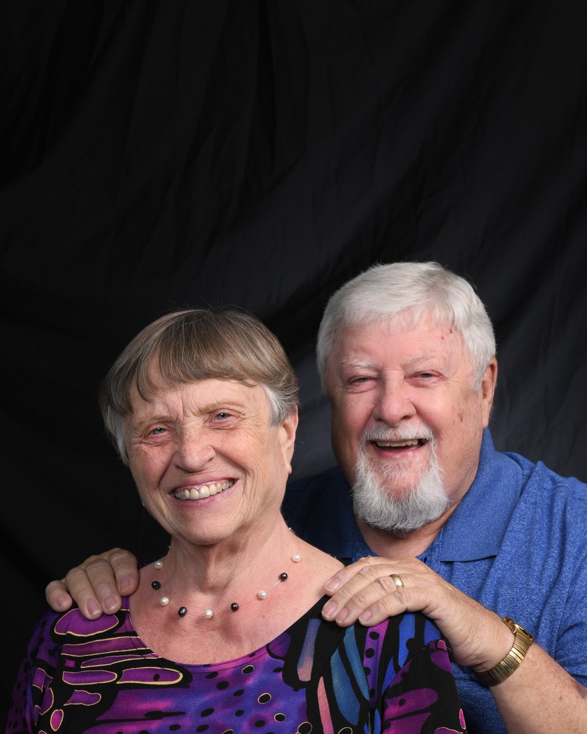 Portrait of a couple laughing together, her hands on his shoulders
