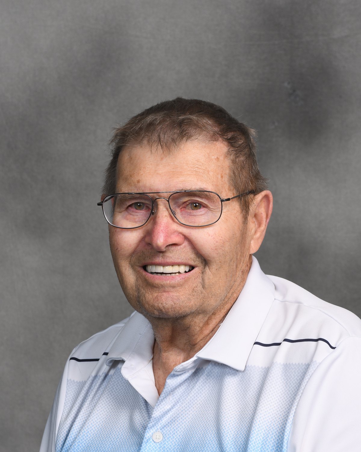 Portrait of a man smiling against a grey studio backdrop